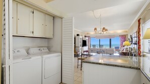 A kitchen with a built-in washer and dryer, a dining area with a view, and a balcony with a railing.