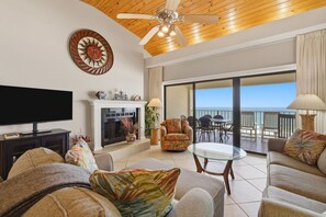 Ein Wohnzimmer mit Fernseher, Sofas, Kamin und einem Balkon mit Blick.