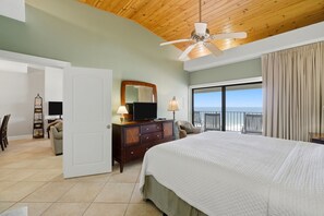 A hotel room with a bed, a television, a dresser, a chair, a balcony with a view, and a ceiling fan. - SHIPWATCH D803 -Beachfront view - NO HASSLE CHECK OUT (Perdido Key)