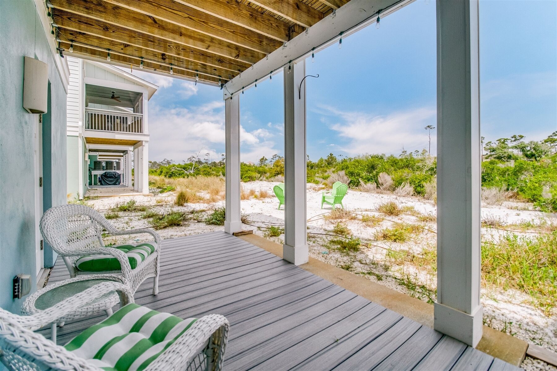 A covered outdoor area with wicker furniture and a view of the beach.