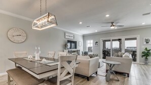 A spacious living area with a dining table, sofas, and a ceiling fan.