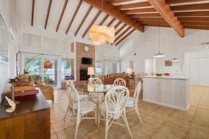Una cocina amplia con comedor, vigas de madera, una isla grande y vistas al exterior.