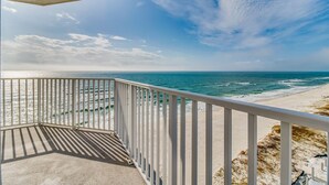 Een balkon met uitzicht op de oceaan en het strand.
