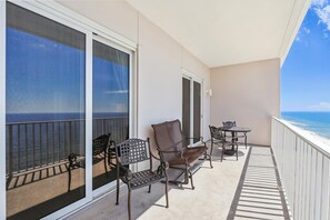 Enjoy the ocean view from this balcony with two comfortable chairs and a small table.