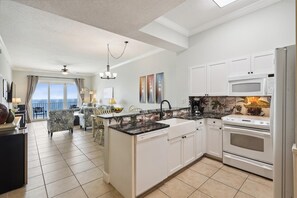 Enjoy meals in the kitchen with a central island, dishwasher, and stove, and dine in the adjacent dining area with a table and chairs overlooking the ocean.