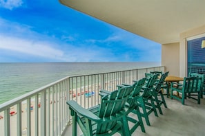 A balcony with green chairs and a table overlooking a beach with umbrellas and people. - NEW LISTING!!! Windemere 901 - Beachfront view - NO HASSLE CHECK OUT (Perdido Key)