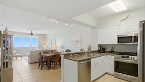 Una cocina moderna con armarios blancos, lavavajillas, estufa y microondas.