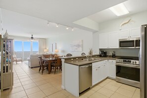 Une cuisine moderne avec des meubles blancs, un lave-vaisselle, une cuisinière et un four à micro-ondes.