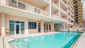 Un hotel con piscina, mobiliario exterior y varios balcones.