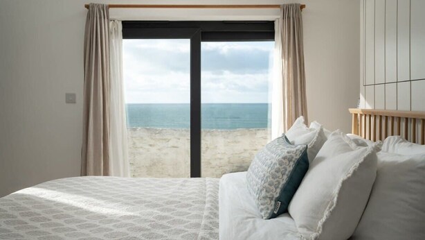 Une chambre à coucher avec un lit, une vue sur la plage et une fenêtre avec des rideaux.