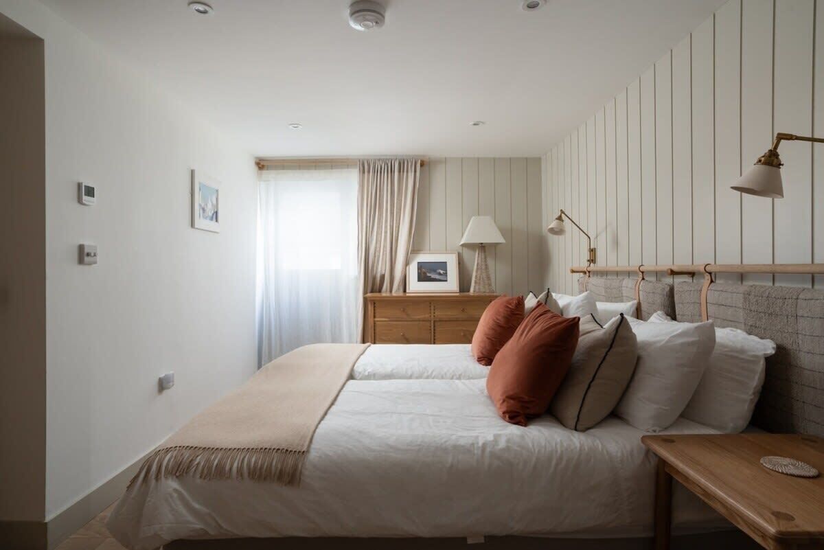 Une chambre à coucher comprenant un lit, des tables de chevet, une commode, une lampe et une coiffeuse.
