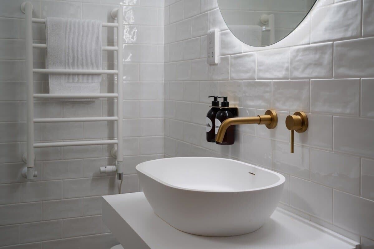 Une salle de bain avec un lavabo blanc, un porte-serviettes et un miroir.