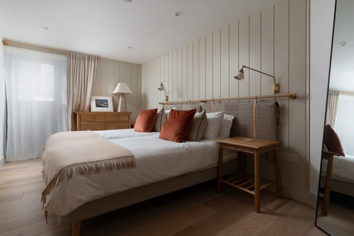 A bedroom with a large bed, bedside tables, a mirror, and a dresser.