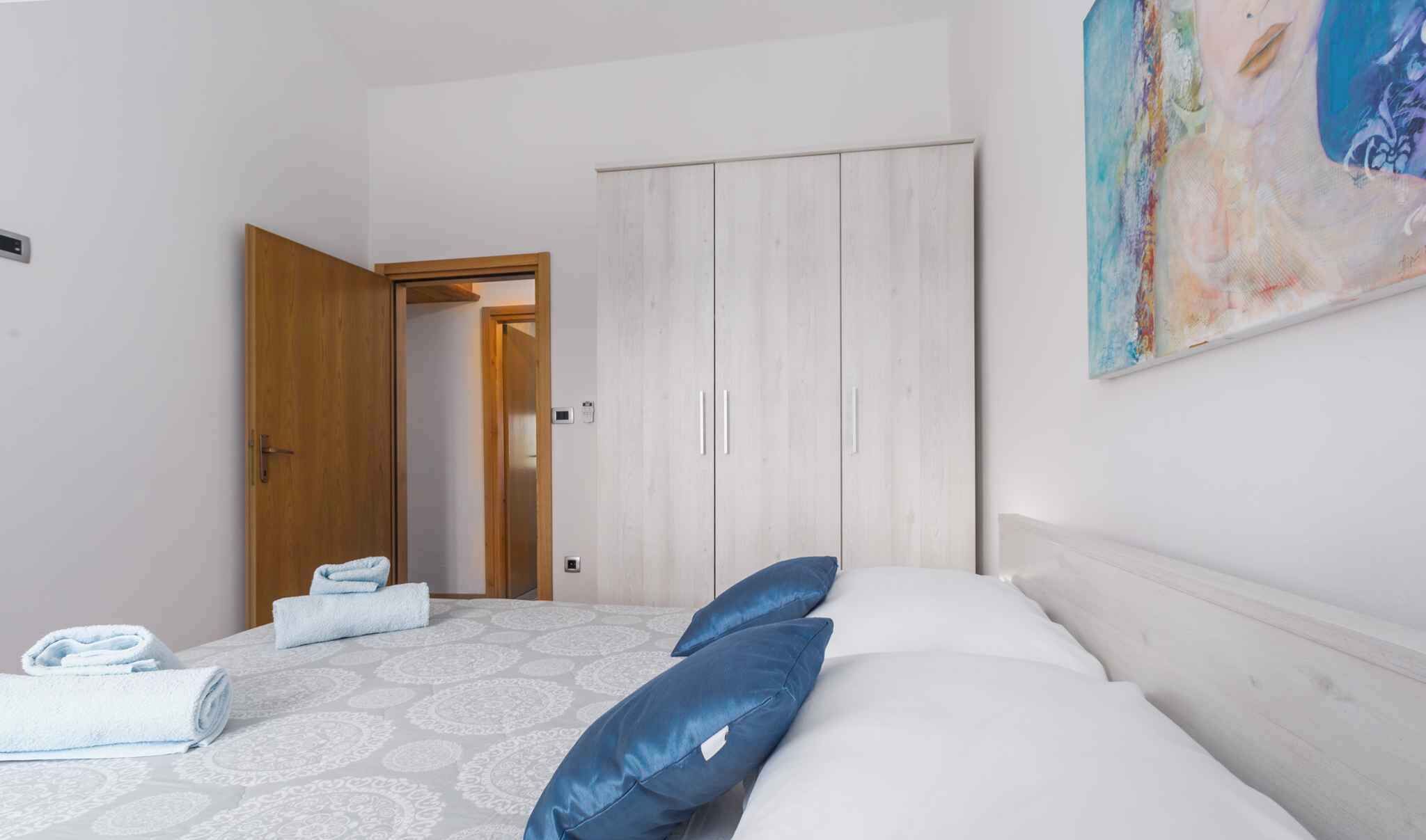 A bedroom with a bed, two pillows, a door, and a painting on the wall.