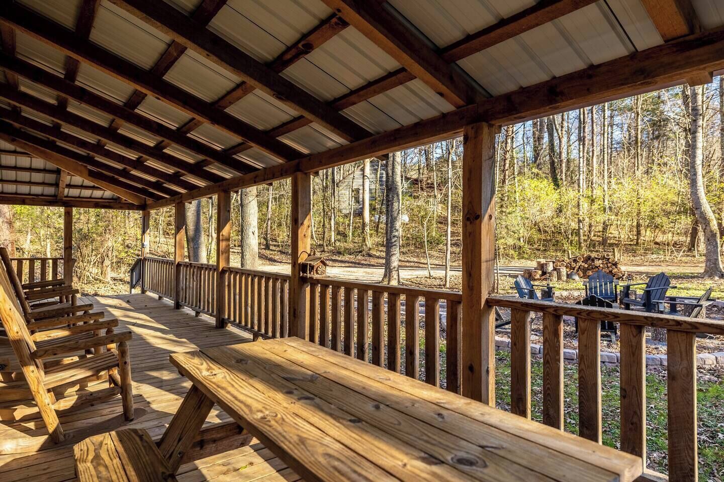 Una terraza cubierta de madera con bancos y vistas a un bosque.