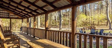 Una terraza cubierta de madera con bancos y vistas a un bosque.