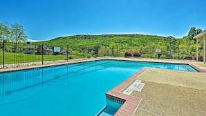 Una piscina con vista libera su una collinetta verde e rigogliosa sullo sfondo.