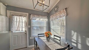 A dining area with a table set for four, a bench, and a vase with flowers. - 1/2 Mi to Fort Campbell: 'State Line Retreat' (Clarksville)