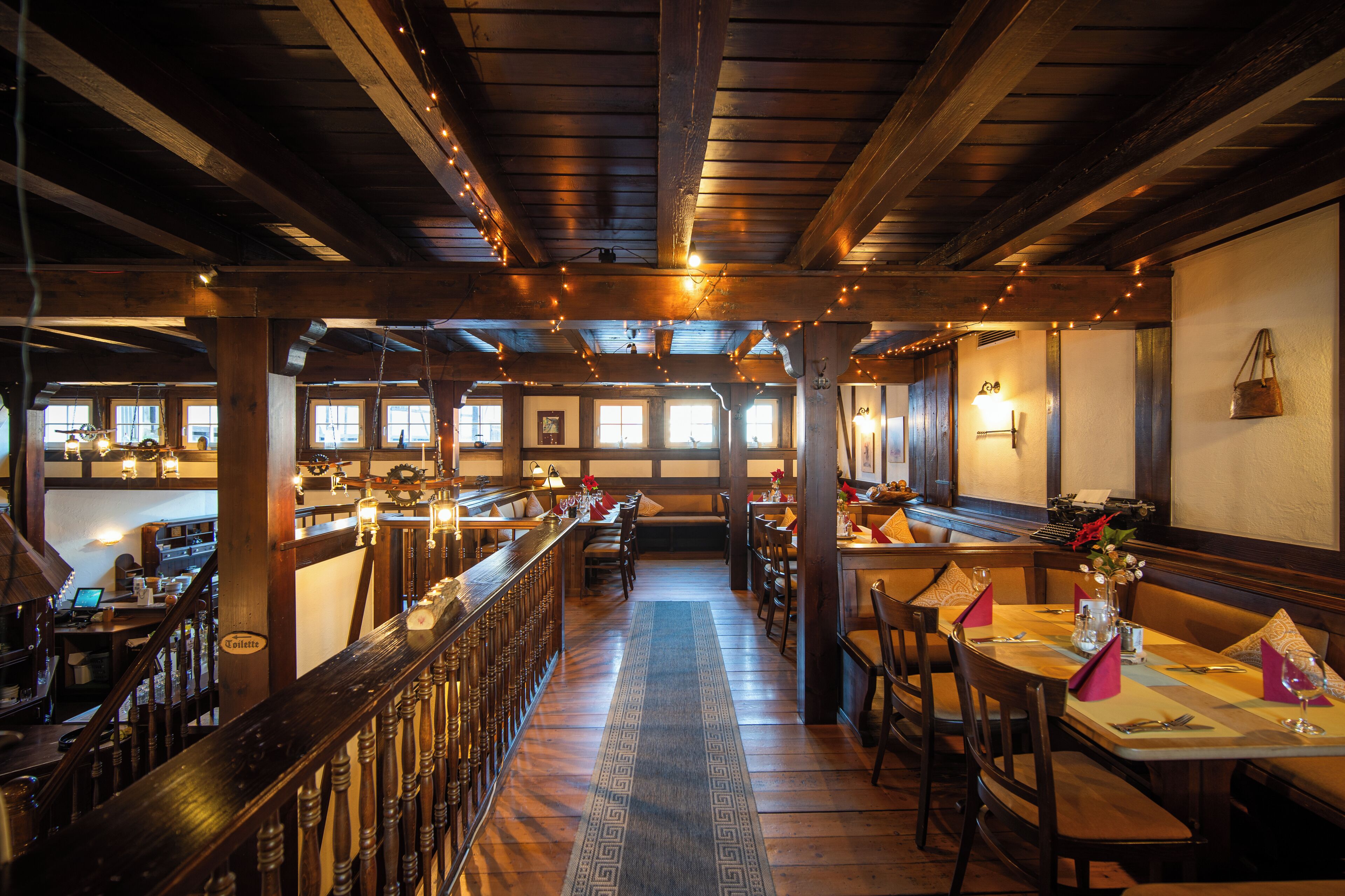 A restaurant interior with wooden beams, a bar area, and tables set for dining.