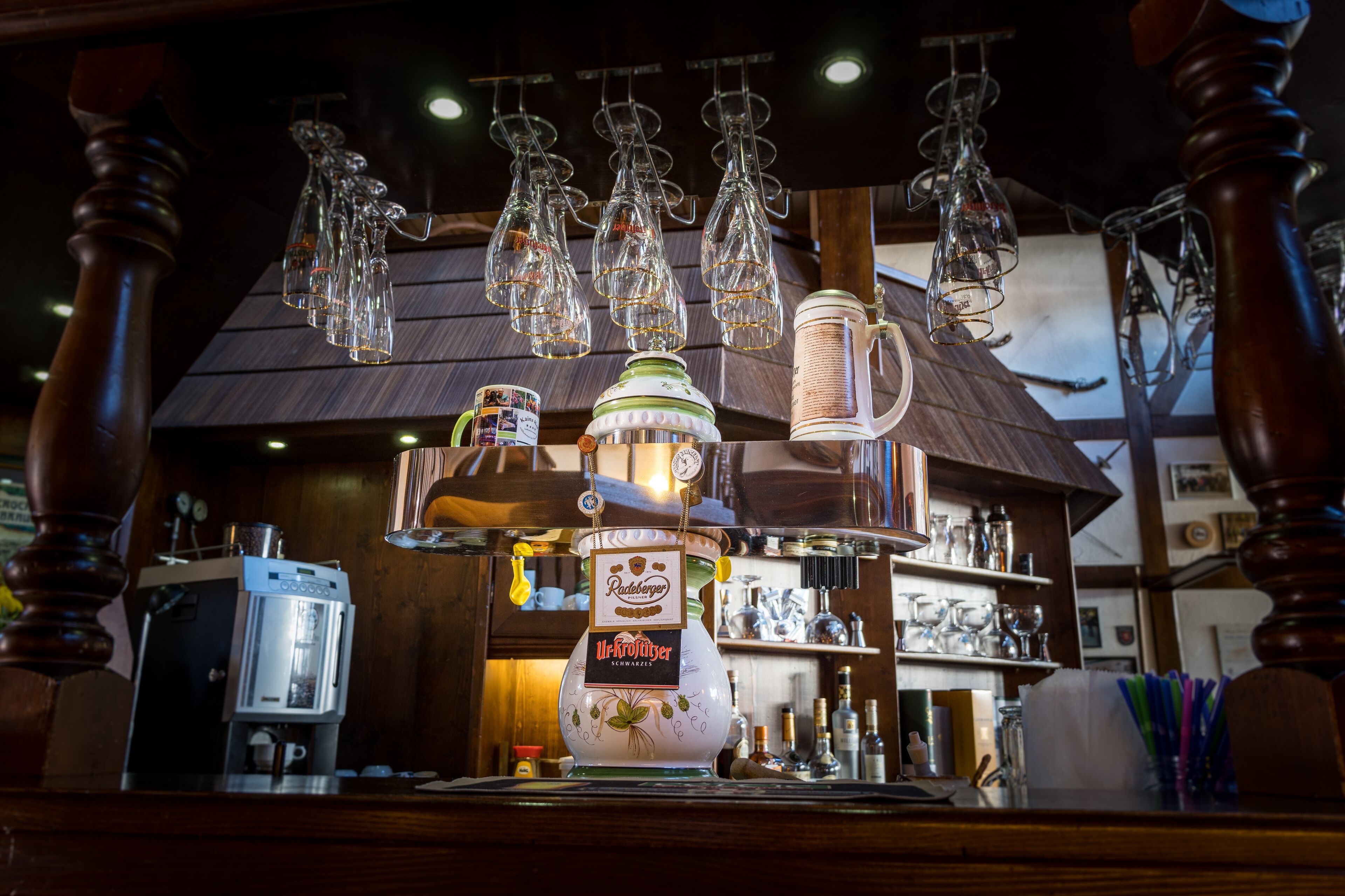 Eine Bar mit einer Kaffeemaschine, einer Tasse und hängendem Glasbesteck.