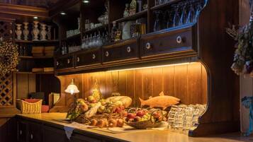A wooden bar area with shelves of glassware, a fish decoration, and various food items on the counter.
