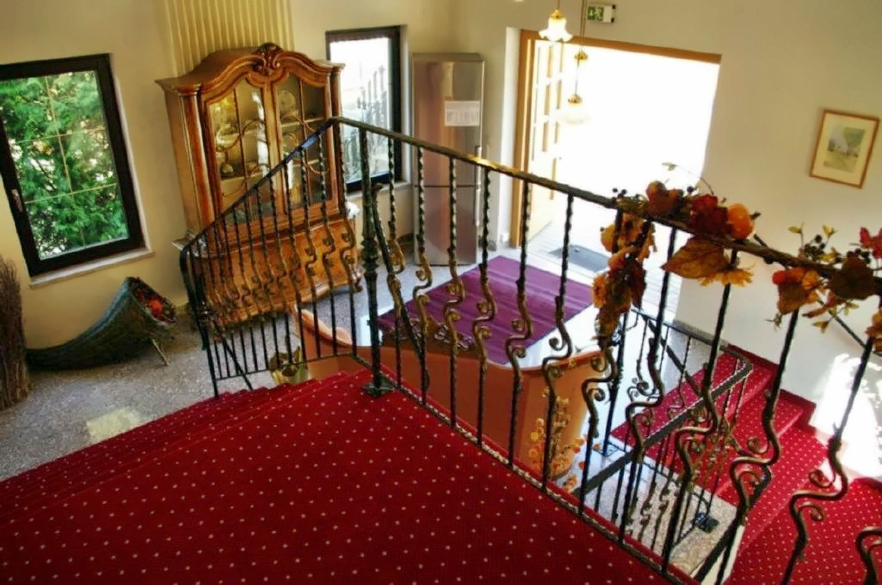A staircase with a red carpet, a wooden chair, and a decorative railing.