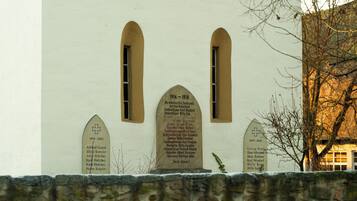 A building with three stone plaques on its facade, each listing names and dates, indicating memorials or historical significance.