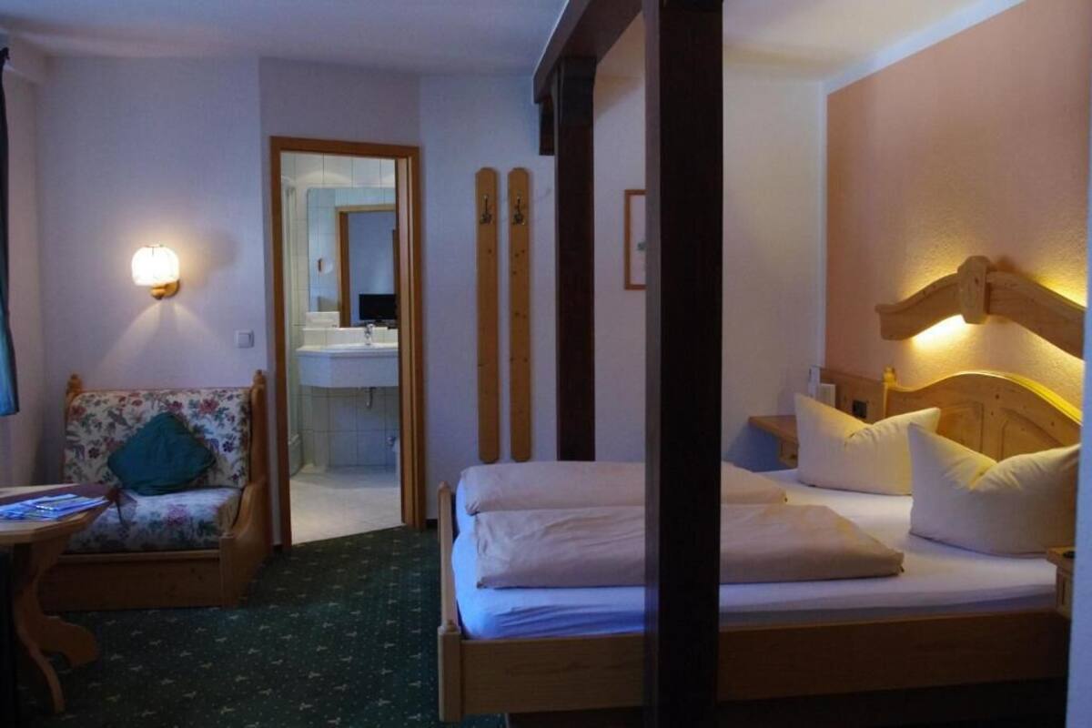 Una habitación de hotel con una cama, una silla, un escritorio y un espejo.
