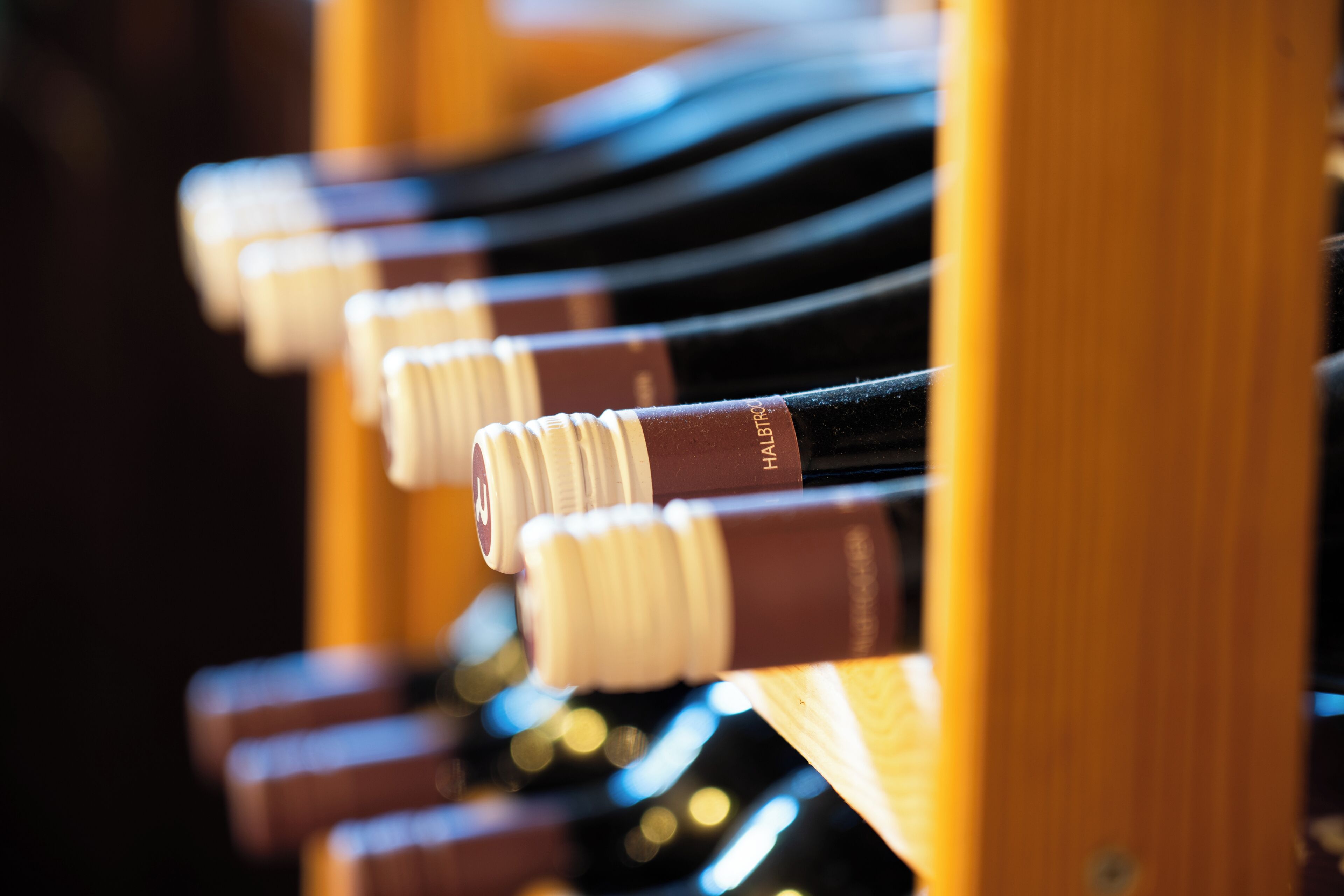 Una hilera de botellas de vino con corchos, dispuestas en un estante de madera.