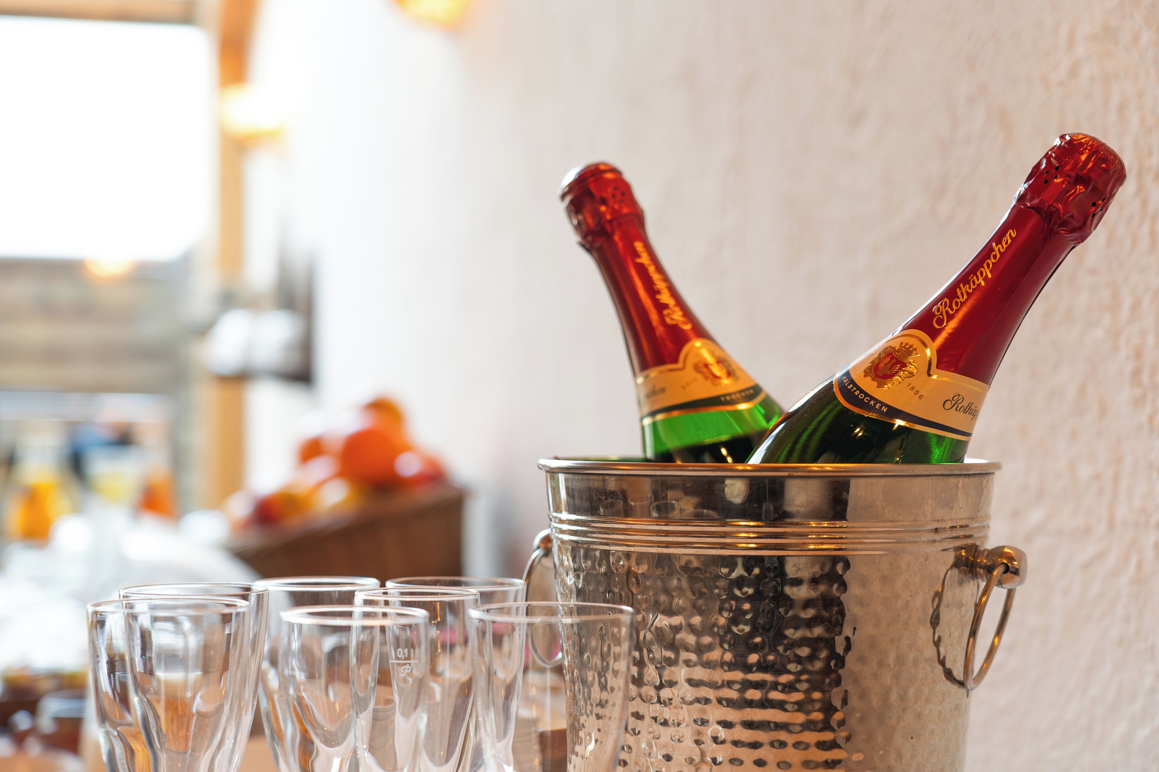 Un seau en métal contenant deux bouteilles de champagne et plusieurs verres vides.