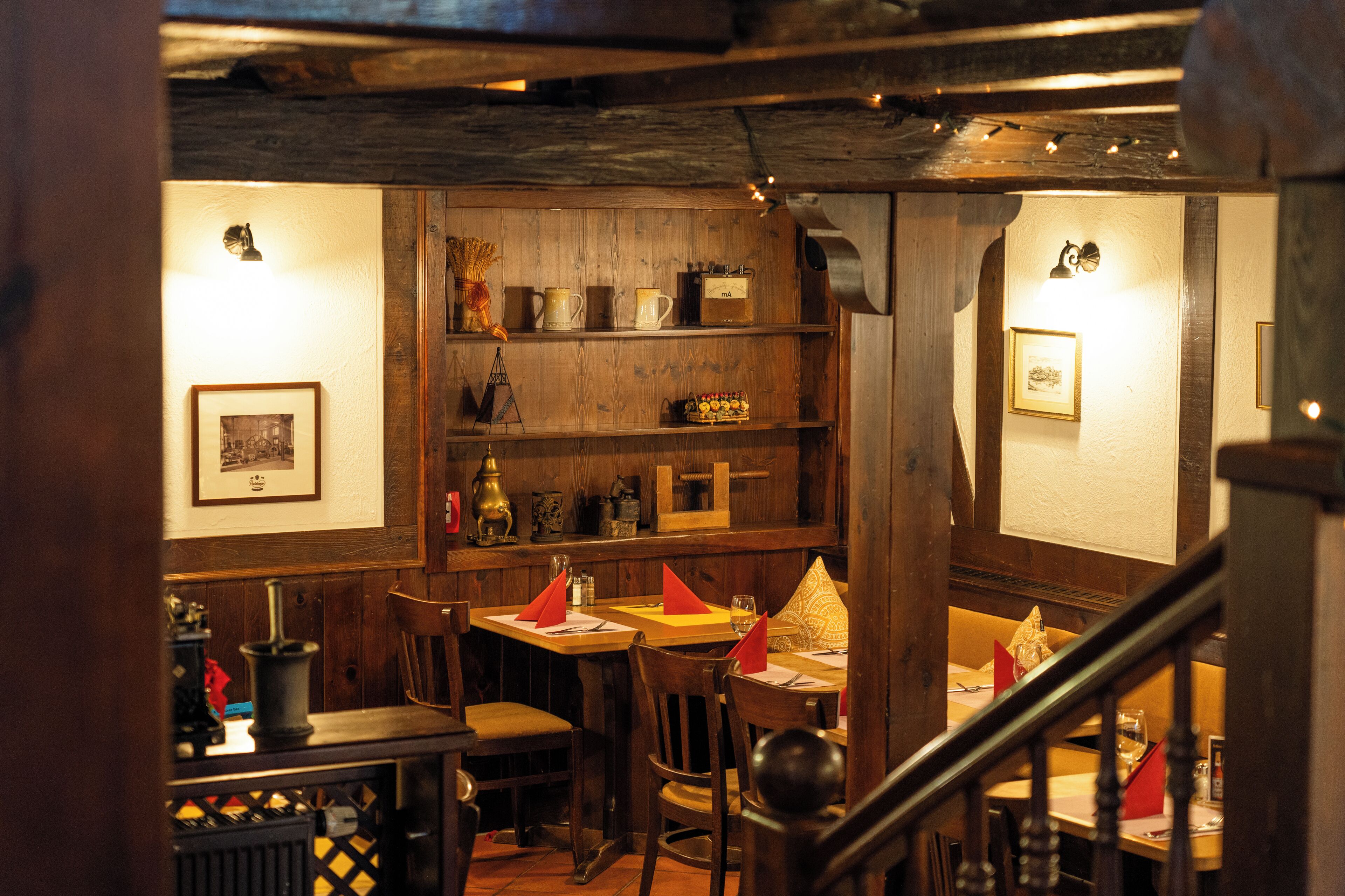 A cozy restaurant with wooden walls and tables, featuring framed pictures and decorative items.