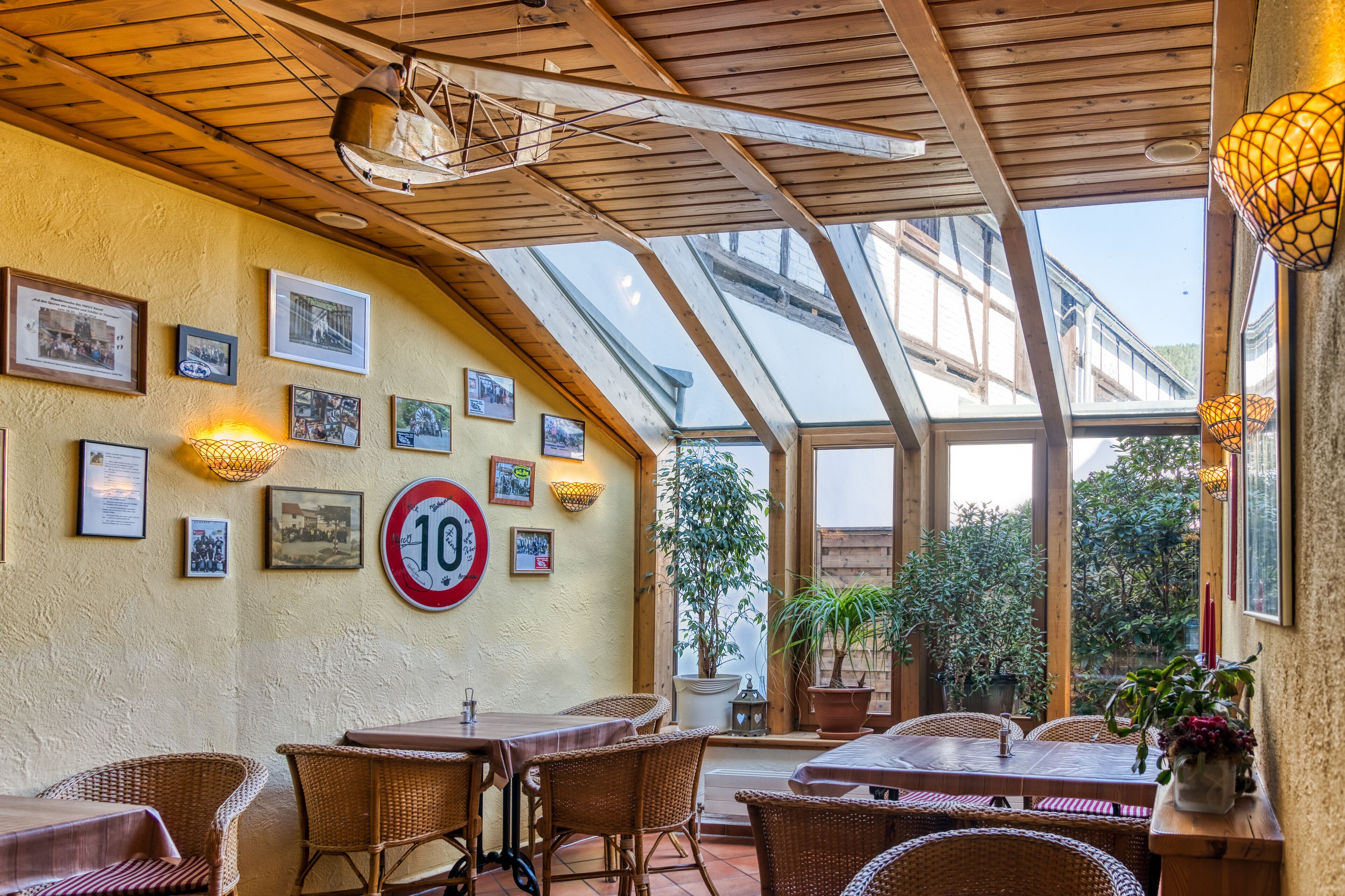 A restaurant with wooden ceiling beams, a glass roof, and wicker furniture.