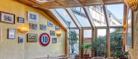 A restaurant with wooden ceiling beams, a glass roof, and wicker furniture.