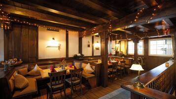 A cozy restaurant with wooden beams, a bar area, and seating arrangements.
