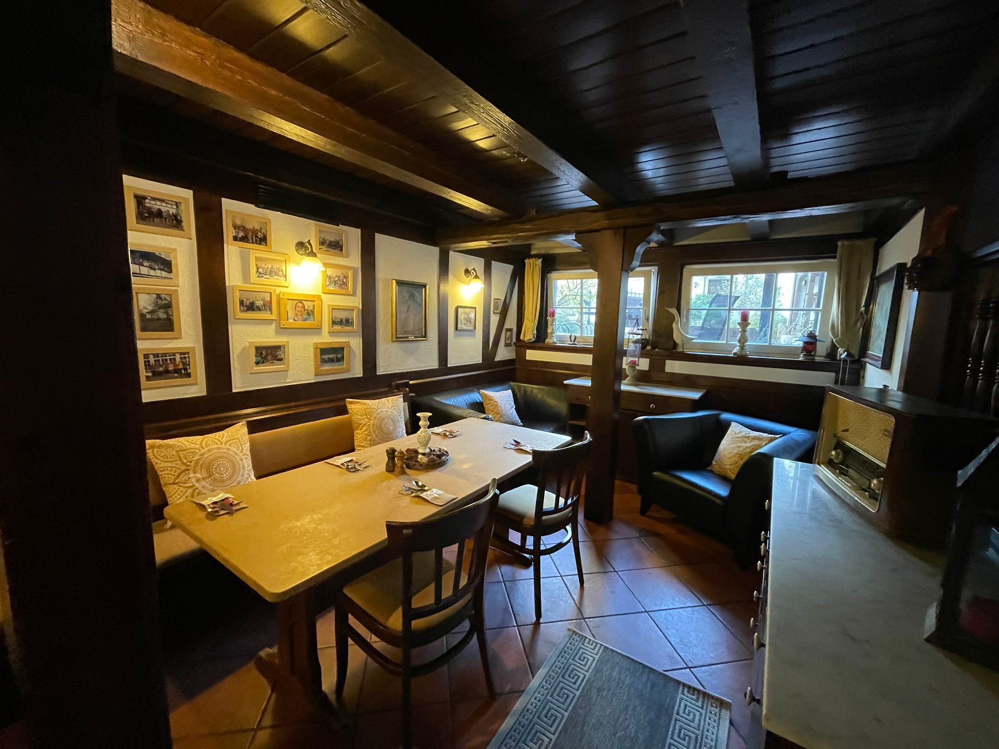 A cozy dining area with a wooden table and chairs, a sofa, and a window with curtains.