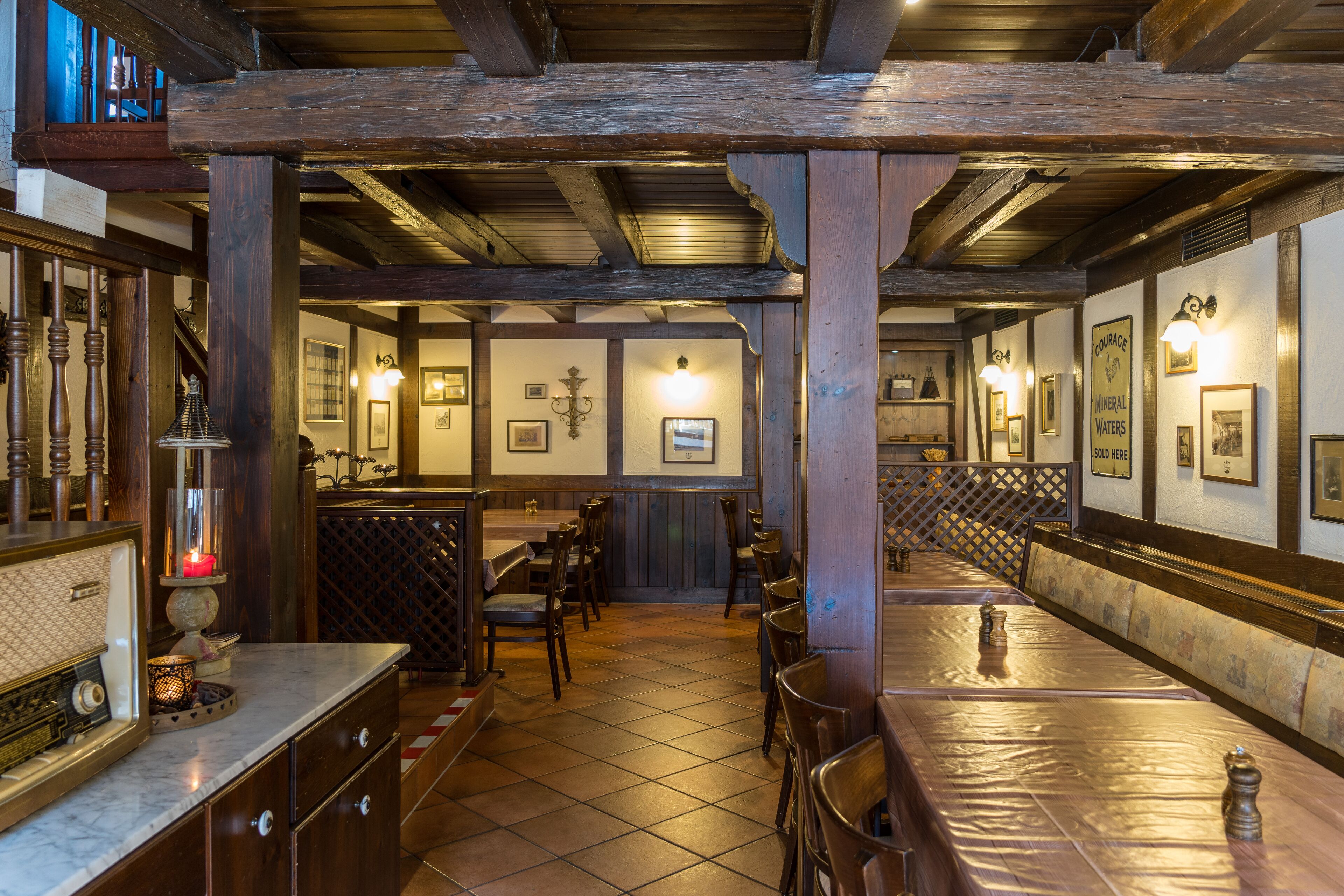 Un restaurant avec des poutres en bois, des carreaux au sol et un long comptoir avec des chaises.