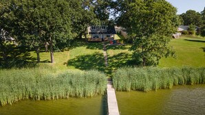 Une jetée en bois s’étendant dans une étendue d’eau, entourée d’une végétation luxuriante et d’arbres.