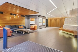 Relax in the stylish lobby area with a comfortable sofa and armchair, a large abstract painting, and a welcoming reception desk.