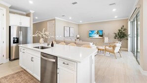 A modern kitchen with white cabinetry, a stainless steel refrigerator, and a central island.