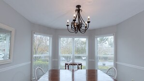 A dining room with a wooden table and chairs, a chandelier, and large windows with blinds. - Charming Townhouse - great walkable area 5 min from Downtown (Columbus)