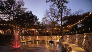 Une cour avec une fontaine, des murs en pierre et des guirlandes lumineuses.