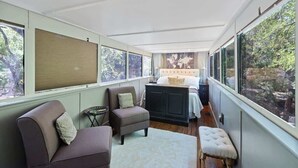 Un dormitorio moderno con un ventanal grande, una cama con cabecera, un sofá y una mesita.