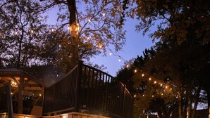 Un escalier en pierre mène à un espace abrité, illuminé de guirlandes lumineuses, et cet ensemble est entouré d’un paysage rocheux et d’arbres.