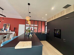 A modern kitchen with a central island, black cabinetry, and pendant lighting.