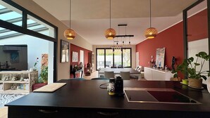 A modern kitchen with a central island, pendant lighting, and a view through large windows. - villa avec piscine pour 6 personnes proche du théatre antique d'orange (Orange)