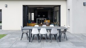 An outdoor patio with a dining table and chairs, a small table with a vase, and a view into the house. - villa avec piscine pour 6 personnes proche du théatre antique d'orange (Orange)