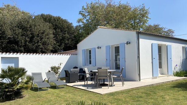A white building with blue shutters, a patio with chairs and tables, and a lawn. - LES MIMOSAS (Saint-Pierre-d'Oléron)