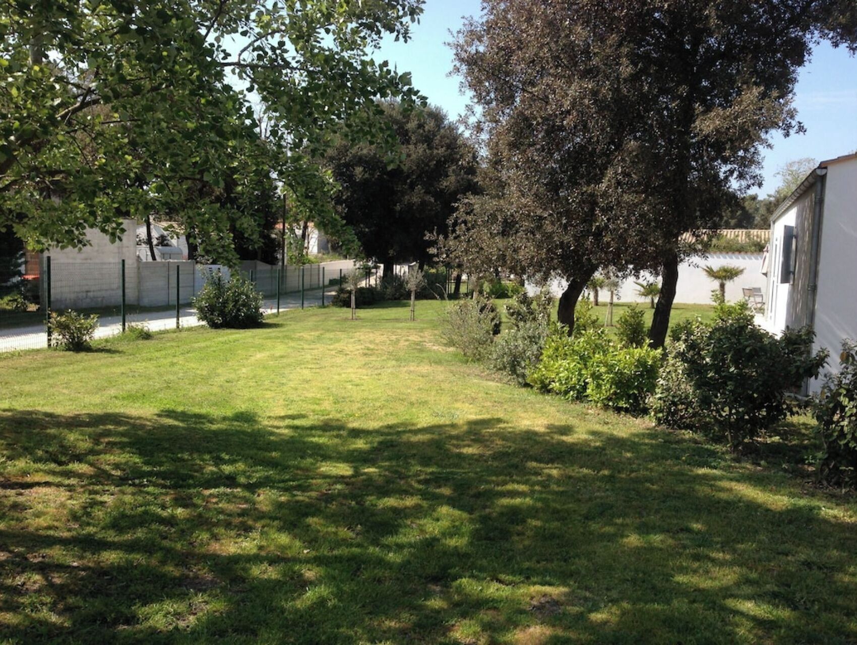 Un espace verdoyant bien entretenu, avec des arbres et un bâtiment blanc.