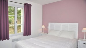 A bedroom with a white bed, purple curtains, and a white headboard. - LES MIMOSAS (Saint-Pierre-d'Oléron)