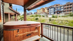 A wooden hot tub on a balcony with a view of multi-story buildings in the background. - Ski in/out! 4 bdrms,Blacksmith Lodge,views,heated garage,internet,8 pers hot tub (Beaverdell)